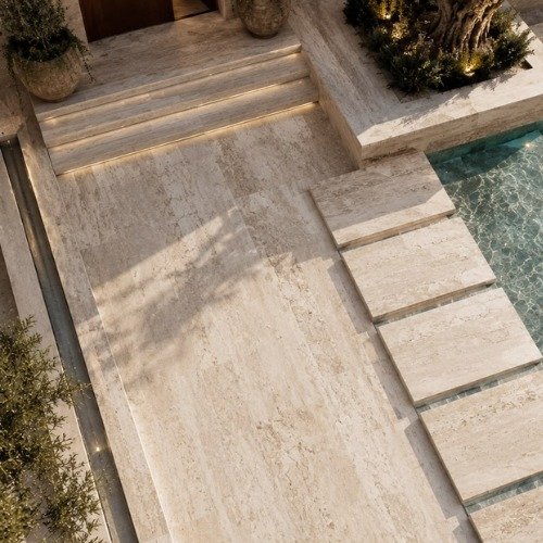 Travertine paving and stepping stones beside a still swimming pool